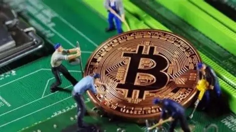 A lone miner inspecting a row of running mining rigs, highlighting the need for constant monitoring and maintenance.